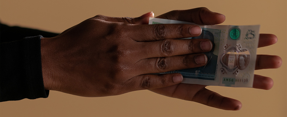 Hands holding a five pound sterling note